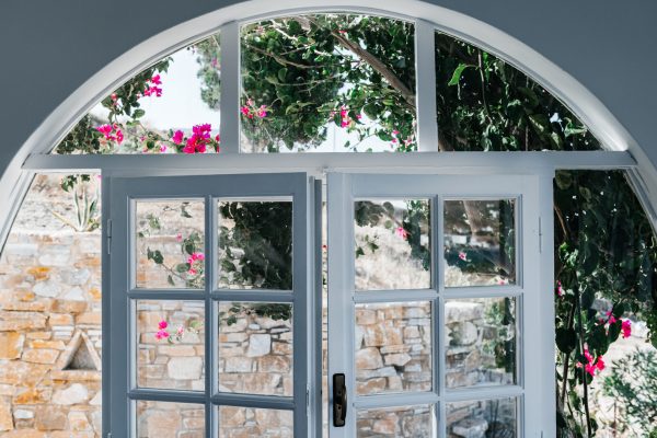 Window with Bougainvillea flowers tree in Greece near traditional Cycladic houses